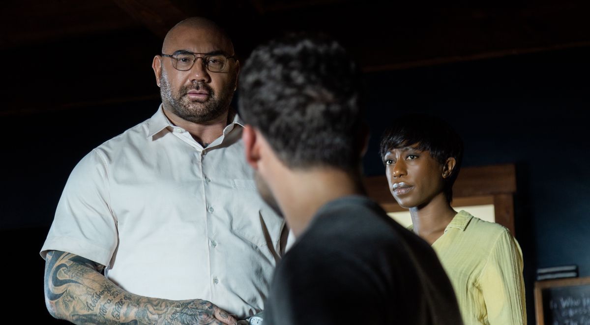 L'invasore domestico Leonard (Dave Bautista) incombe sul suo prigioniero Eric (Jonathan Groff) mentre la compagna di Leonard Sabrina (Nikki Amuka-Bird) guarda in Knock at the Cabin