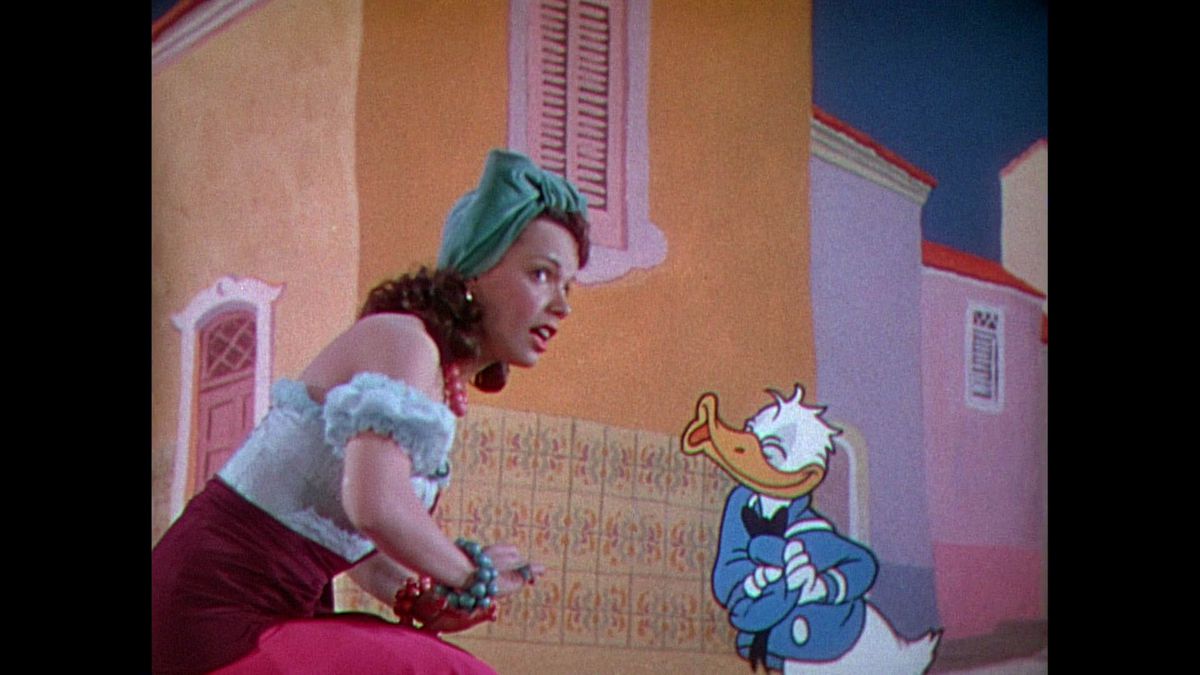 Paperino, arruffato e sudato, chiude gli occhi e si china per un bacio dalla cantante Aurora Miranda in I tre caballeros