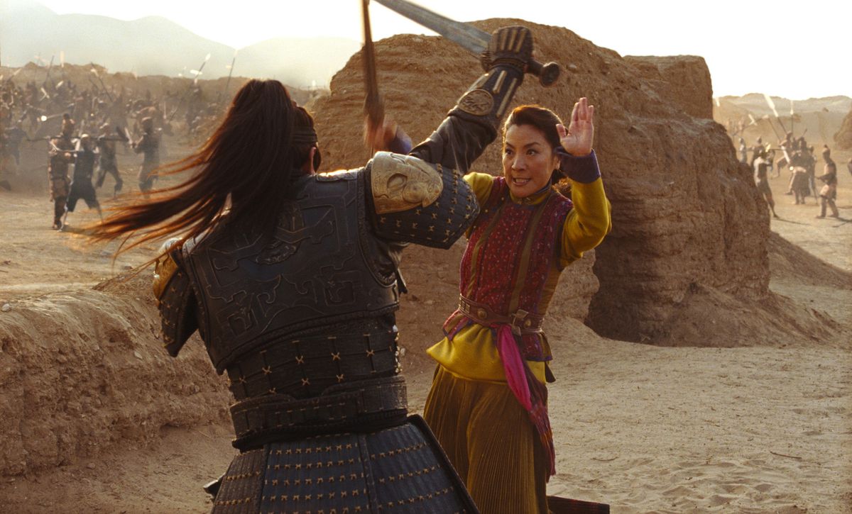 Michelle Yeoh in The Mummy: Tomb of the Dragon Emperor combatte con la spada un antico guerriero in armatura borchiata mentre si trova sullo sfondo del deserto