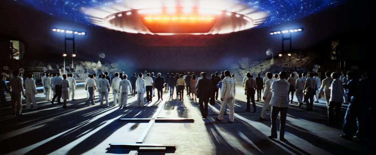 Una folla di scienziati osserva un'astronave luminosa in Incontri ravvicinati del terzo tipo