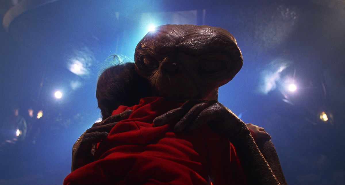 ET abbraccia Elliot nella sua felpa rossa mentre è in piedi davanti alla sua astronave