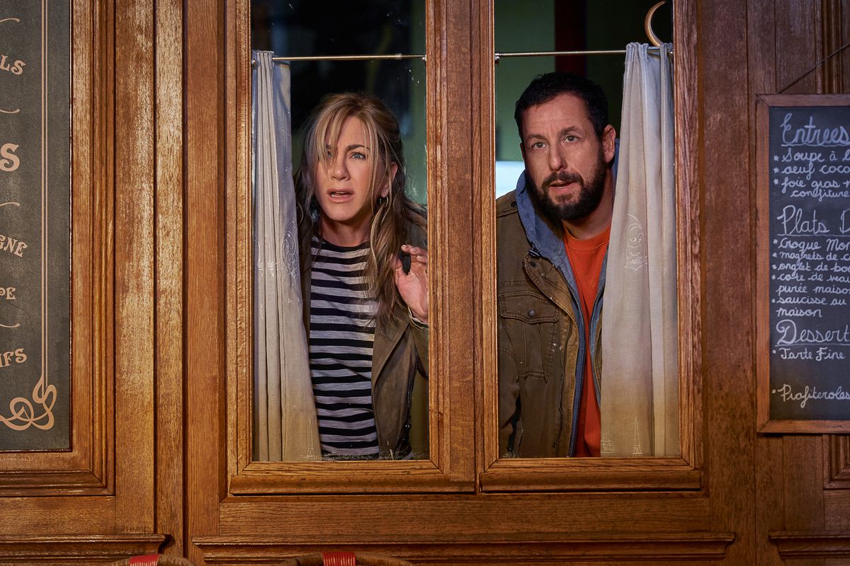 Jennifer Aniston e Adam Sandler sbirciano attraverso una finestra in Murder Mystery 2.