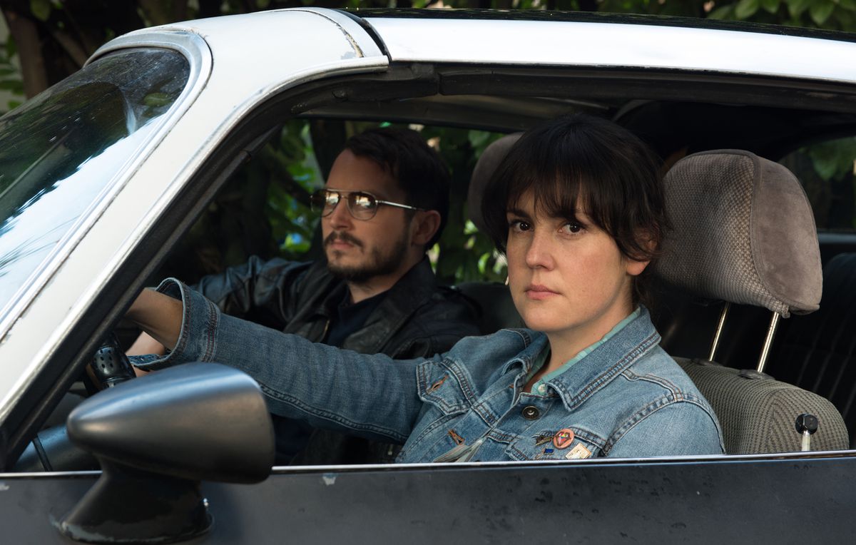 (LR) Elijah Wood e Melanie Lynskey seduti al volante di un'auto in Non mi sento più a casa in questo mondo