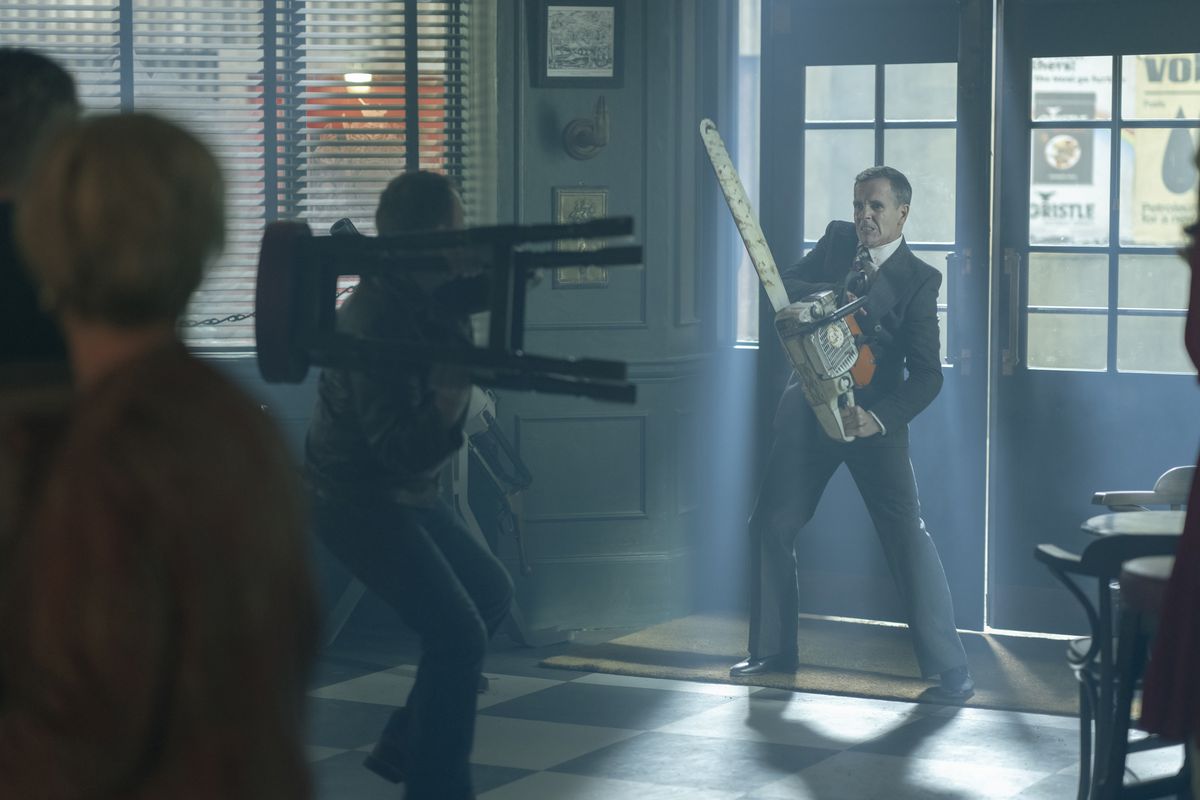 Un uomo si trova all'ingresso di un pub con una motosega mentre un altro uomo si prepara a lanciargli uno sgabello nello show della HBO Max Pennyworth.