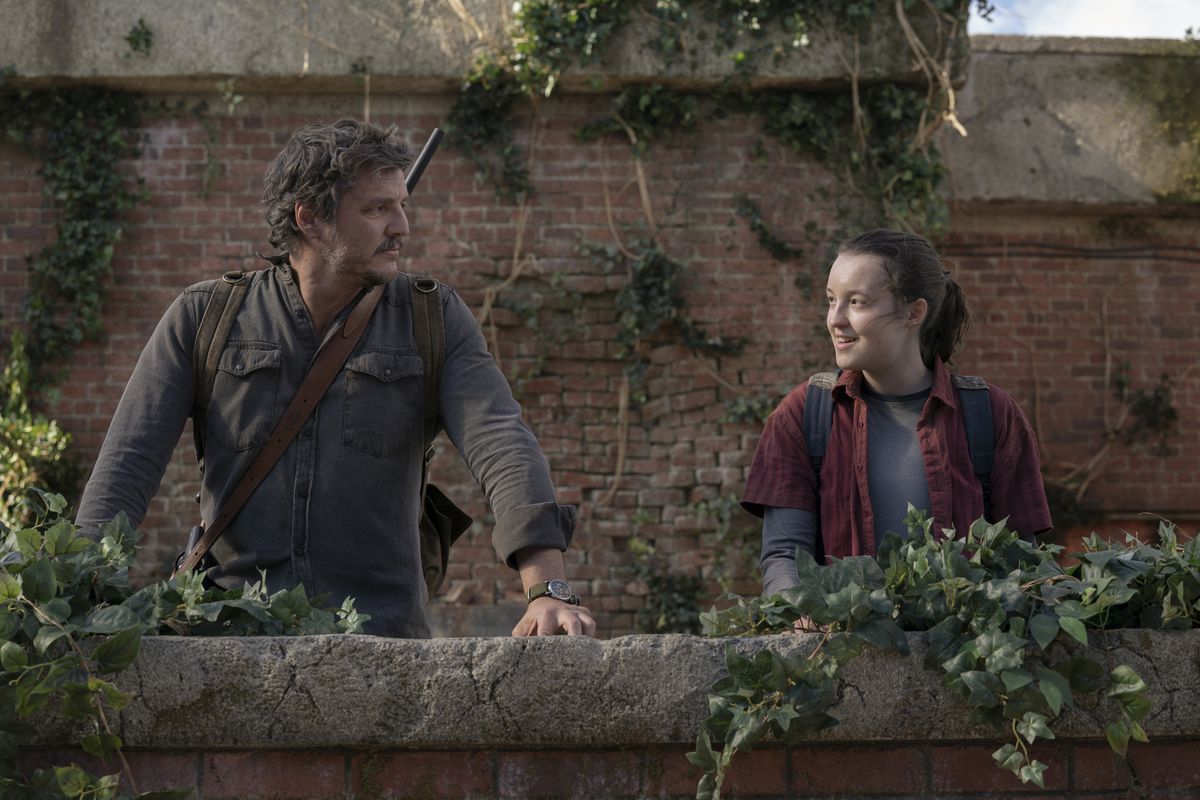 Joel ed Ellie si guardano e sorridono mentre si trovano sul bordo di un balcone coperto di edera in The Last of Us della HBO