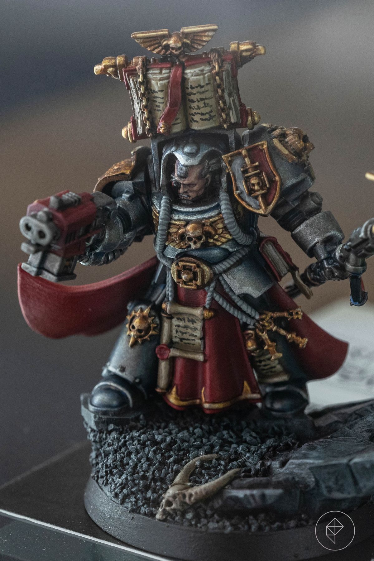 A sliver armored Space Marine from AdeptiCon 2023. He wears a massive book on his backpack, and his armor has a white sheen to it along the edges.