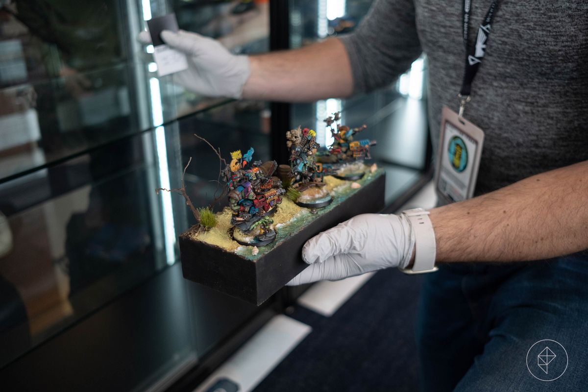 An employee wearing white gloves gingerly places an award-winning miniature back on display.