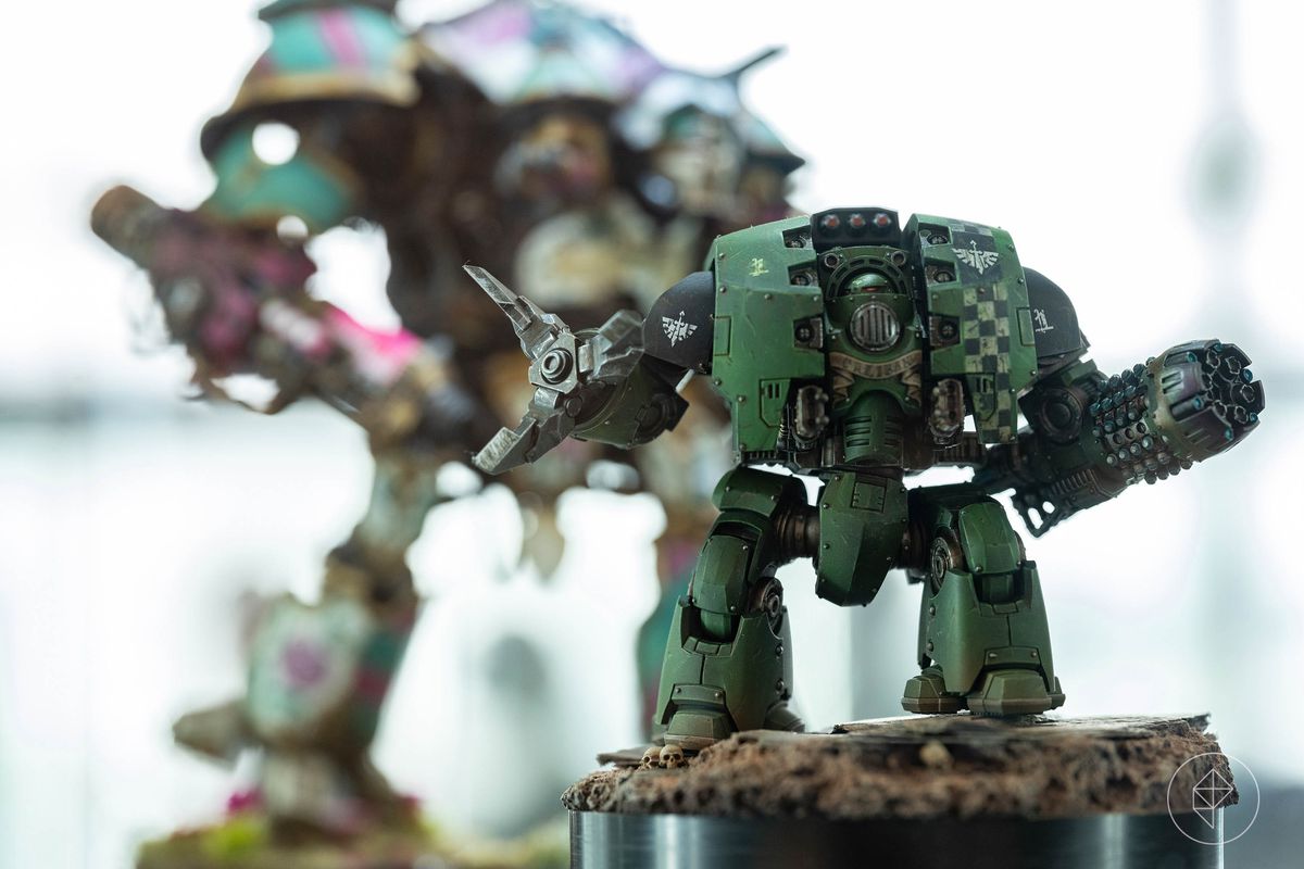 A Dark Angels deredeo pattern dreadnought, all thick shoulders and round profiles. It is painted in green and black, with a light dusting of pigment on the feet to connect it with its base — which has a few skulls glued on for good measure.