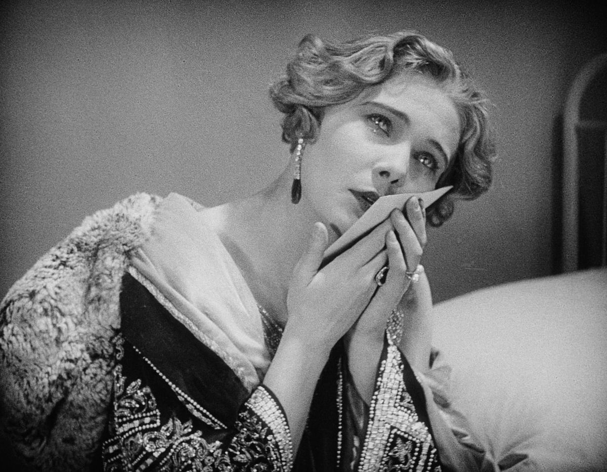 Una donna con le lacrime agli occhi stringe un biglietto e se lo avvicina alla guancia in Spione