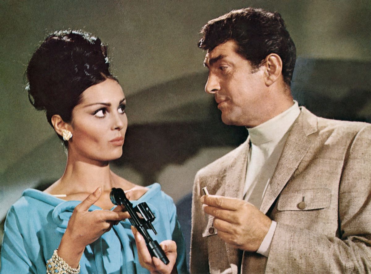 Matt Helm carica un proiettile in un revolver per una donna dai capelli neri con un vestito blu