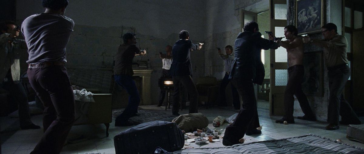 Spie israeliane e palestinesi sollevano armi in una situazione di stallo in una stanza scarsamente illuminata con detriti sul terreno a Monaco