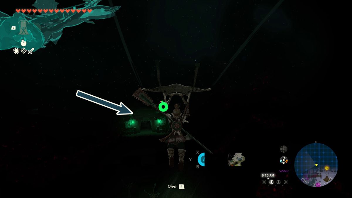 Una freccia indica l'ingresso di una caverna nell'oscurità con l'unica luce nelle vicinanze delle lanterne verdi in Lacrime del Regno