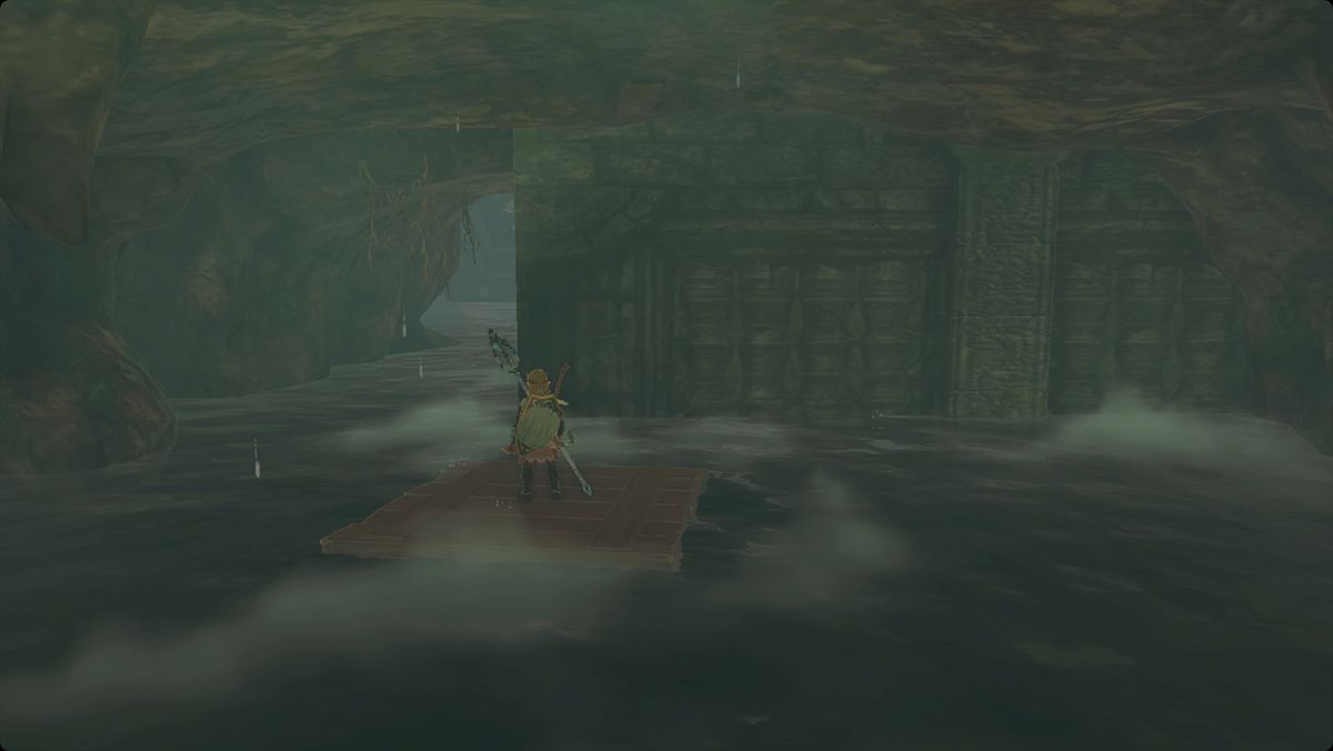 The Legend of Zelda: Tears of the Kingdom Link in piedi su una zattera di legno galleggiante nella Cape Cales Cliffside Cave