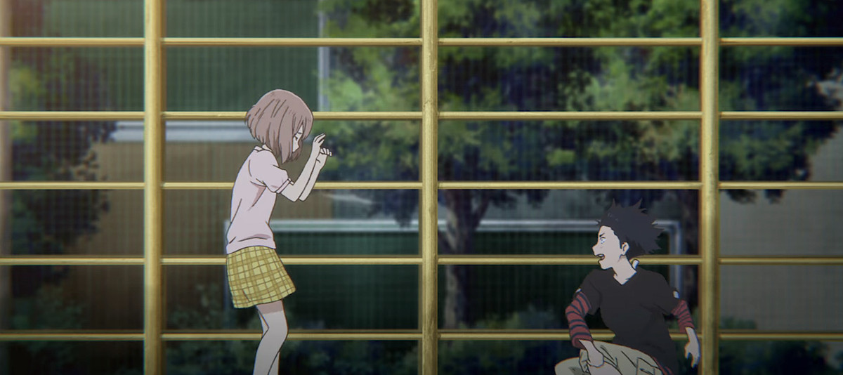 Shôya Ishida, liceale dai capelli a punta, lancia terra alla compagna di classe Sorda Shoko Nishimiya e le urla contro davanti a una griglia di recinzione gialla in una scena di flashback in A Silent Voice