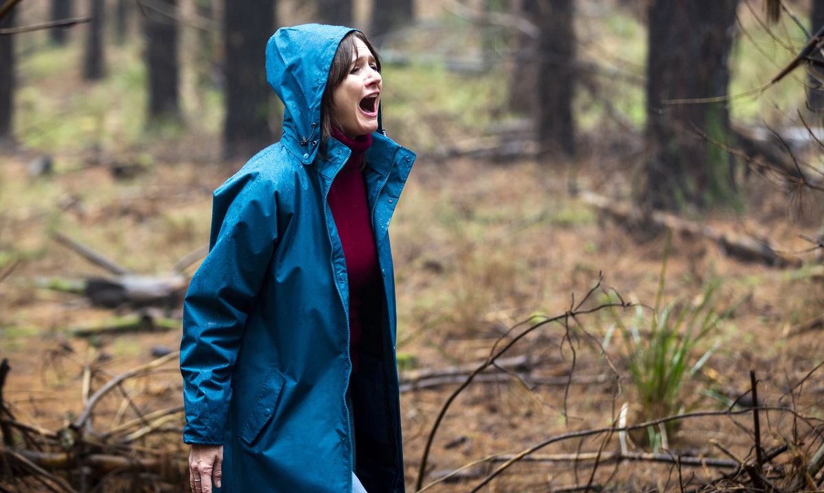 Emily Mortimer in Relic si trova nel bosco in una giacca blu brillante, urlando.