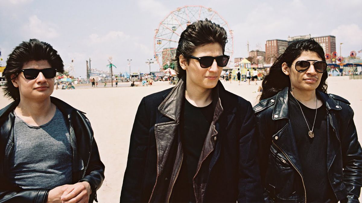 Tre fratelli Angulo indossano occhiali da sole e giacche di pelle su una spiaggia di Coney Island