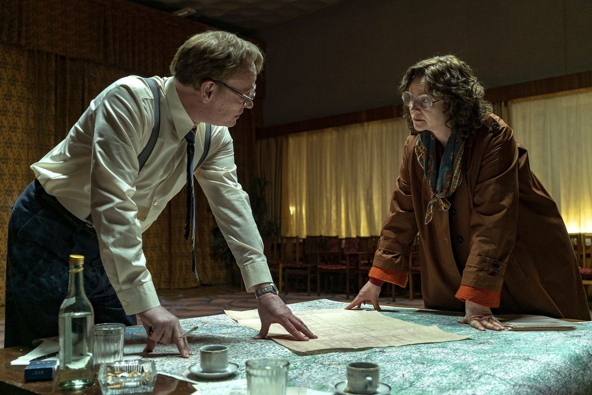 Mentre Valery Legasov e Ulana Khomyuk, Jared Harris ed Emily Watson stanno in piedi su un tavolo coperto di documenti a Chernobyl