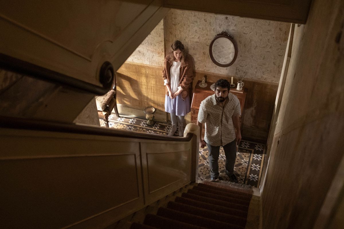 Due persone in fondo a una scala, guardando in alto, nel film horror di Romola Garai, Amuleto.