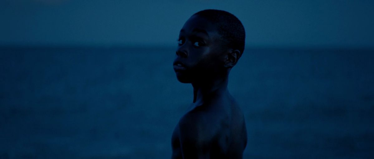 un giovane ragazzo nero si guarda alle spalle mentre si trova di fronte all'oceano in Moonlight (2016)