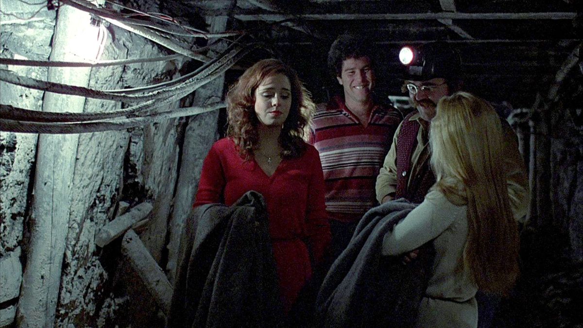 Quattro persone camminano lungo un pozzo minerario