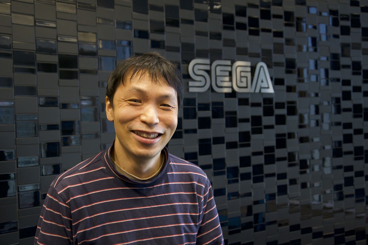 Hideaki Kobayashi si trova di fronte al logo Sega su un muro