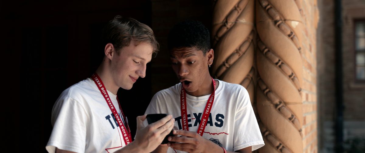 Two of the subjects from Boys State get excited over the latest news on their phones.