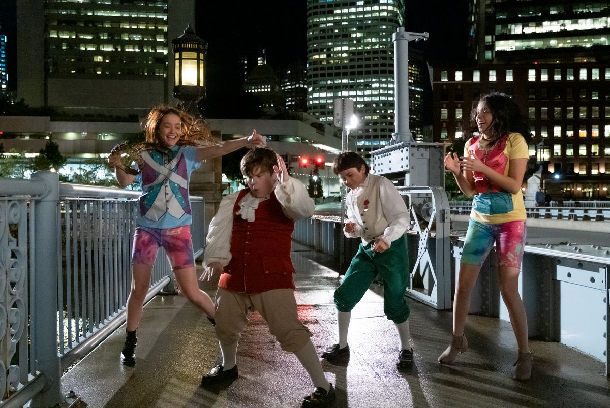 quattro bambini vestiti di novità ballano su un molo