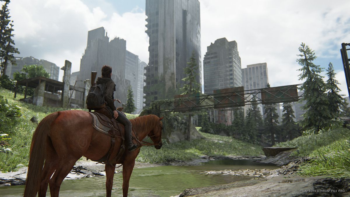 Ellie, a cavallo, in piedi fuori da una città invasa dalla natura in The Last of Us Part 2
