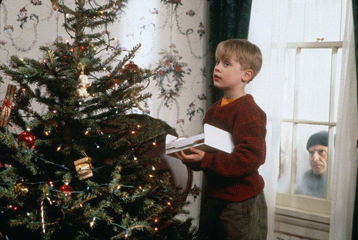 Kevin (Macaulay Culkin) decora un albero mentre Harry (Joe Pesci) guarda attraverso una finestra.