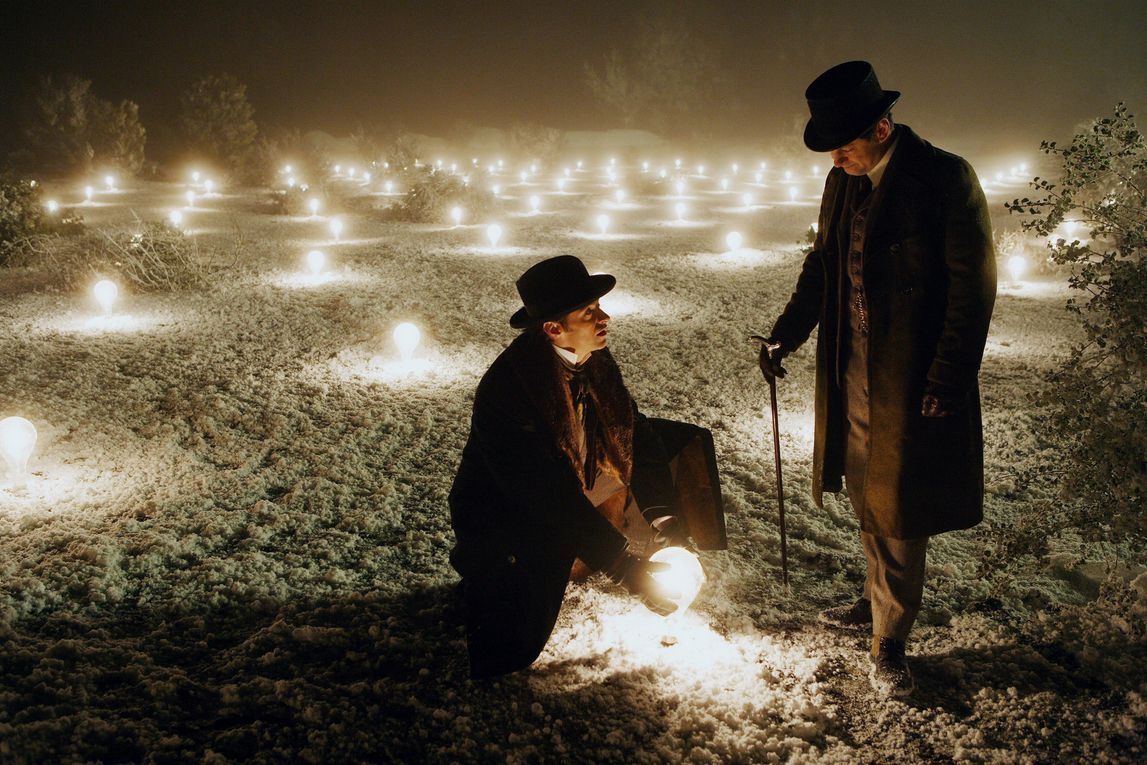 un uomo tiene in mano una sfera luminosa in The Prestige, accanto a un altro uomo nella neve