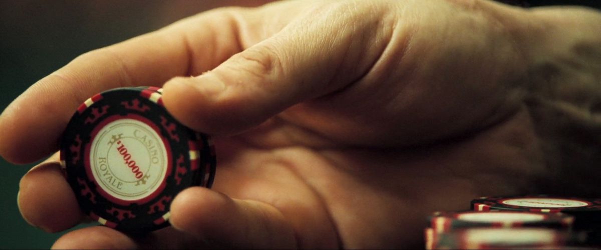 a close up of a hand holding a poker chip in Casino Royale