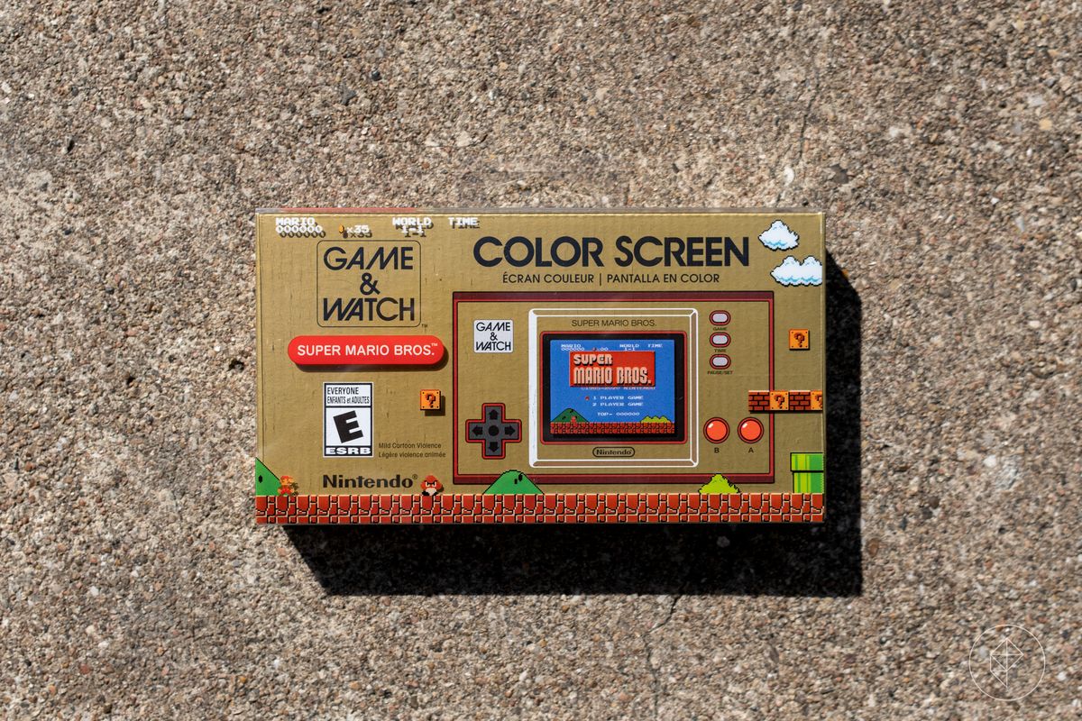 La parte anteriore di una console Nintendo Game & Watch: Super Mario Bros. in scatola fotografata su cemento