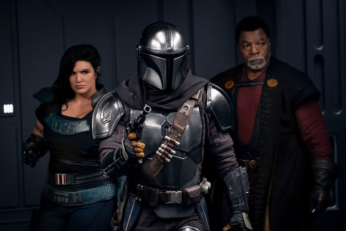 Cara Dune, The Mandalorian, and Greef Karga stand in an elevator with their blasters up