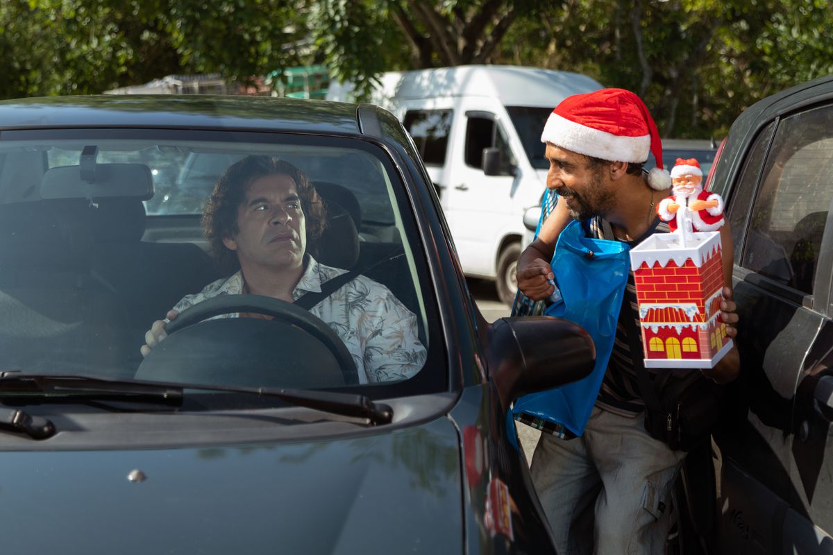Leandro Hassum siede nella sua macchina e sembra allarmato mentre qualcuno con un cappello da Babbo Natale lo affronta