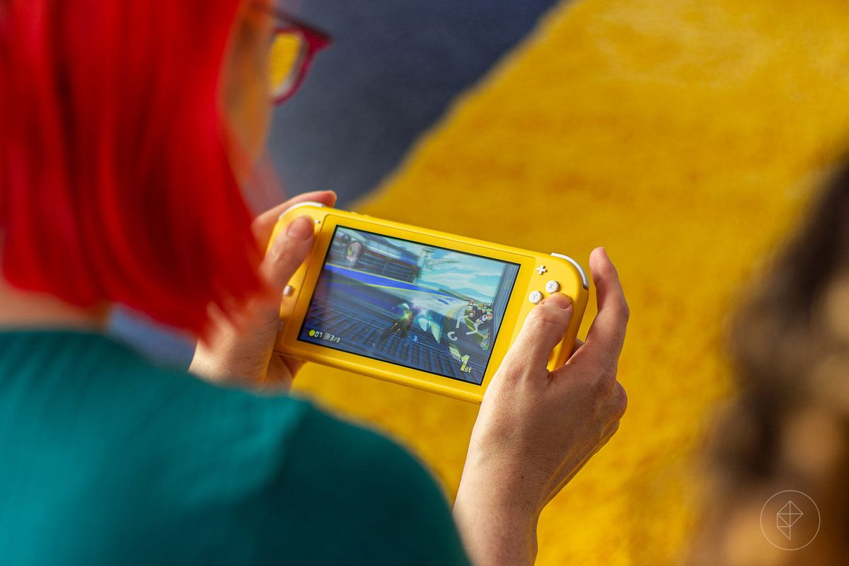 a red-haired woman playing the Nintendo Switch Lite