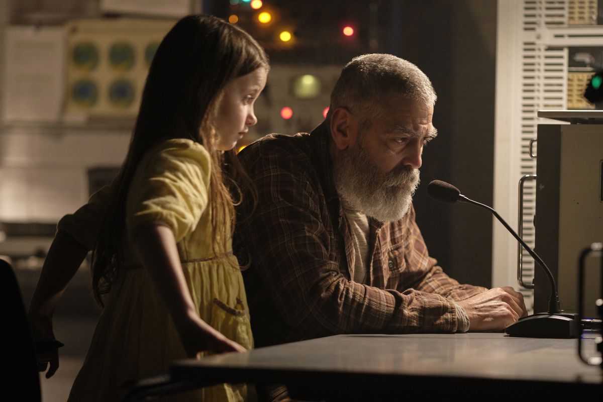 Un George Clooney barbuto e una bambina siedono davanti a un microfono sperando di contattare una stazione spaziale in The Midnight Sky
