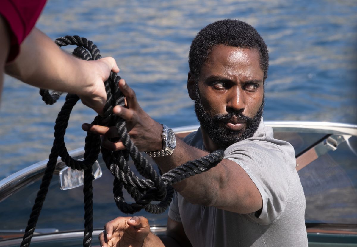 John David Washington è in piedi su una barca, afferrando una spessa corda nera in Tenet