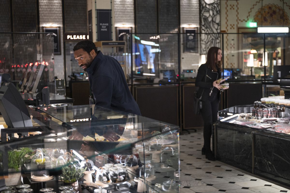 Anne Hathaway e Chiwetel Ejiofor guardano attraverso il bancone dei gioielli in un negozio a Locked Down