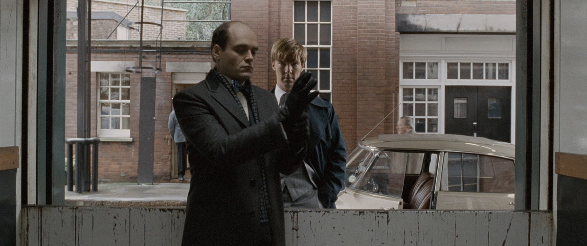 Tinker, Tailor, Soldier, Spy: Peter (benedict cumberbatch) guarda un uomo che indossa un guanto attraverso la finestra