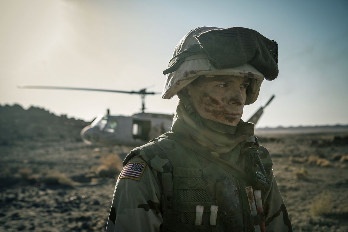 Muddy Tom Holland in tenuta militare in Iraq in piedi davanti a un elicottero