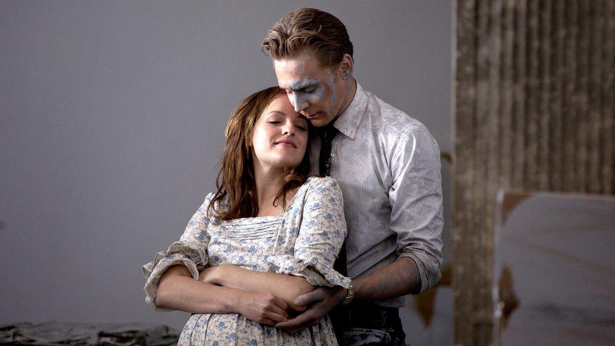 Tom Hiddelston as Robert Laing holding his wife while covered in paint.