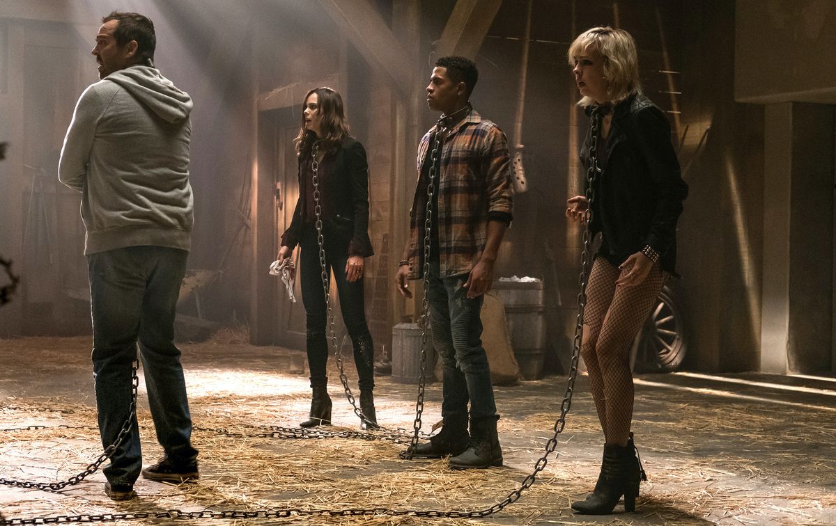 Four potential Jigsaw victims stand in a barn, wearing metal collars and chains, in Jigsaw