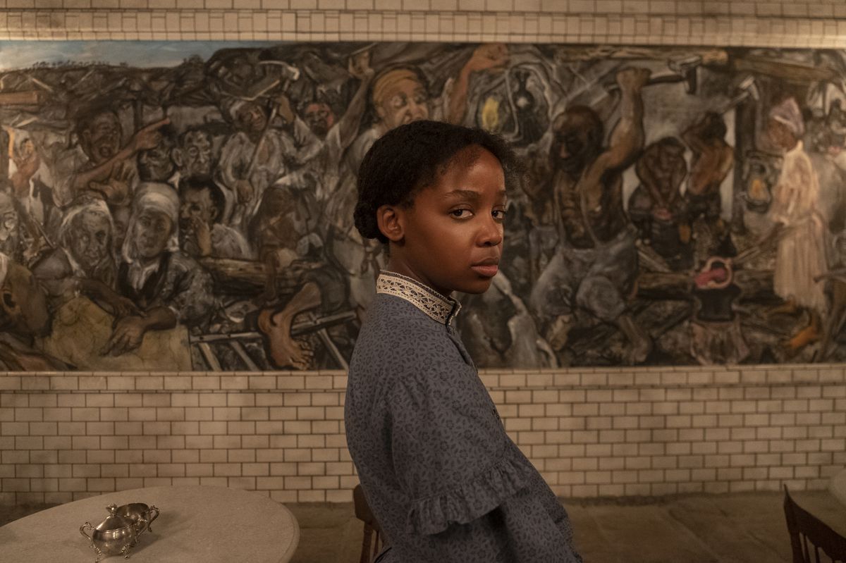 Cora (Thuso Mbedu) si trova di fronte a un elaborato murale in una stazione ferroviaria sotterranea in The Underground Railroad di Barry Jenkins