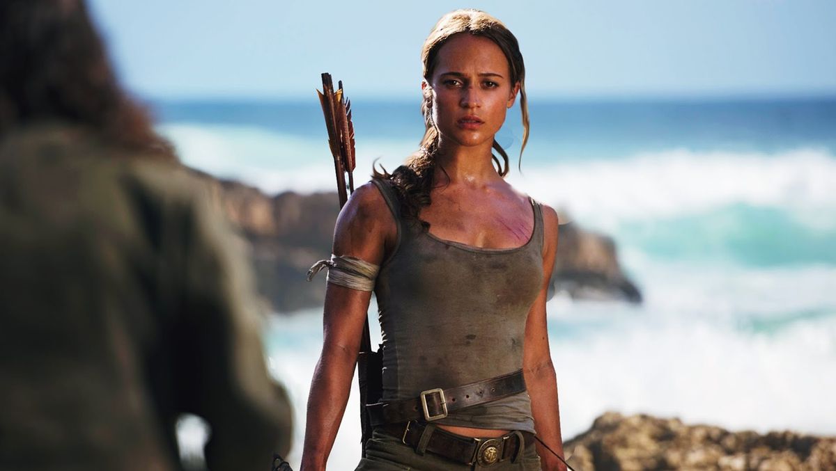 Alicia Vikander nei panni di Lara Croft, in canotta e con archi mentre si trova di fronte all'oceano, nel film Tomb Raider del 2018