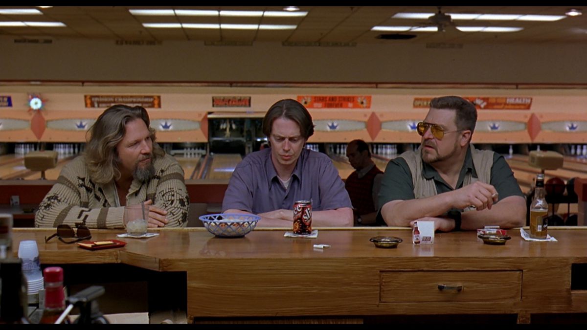 three men sitting at a bowling alley counter