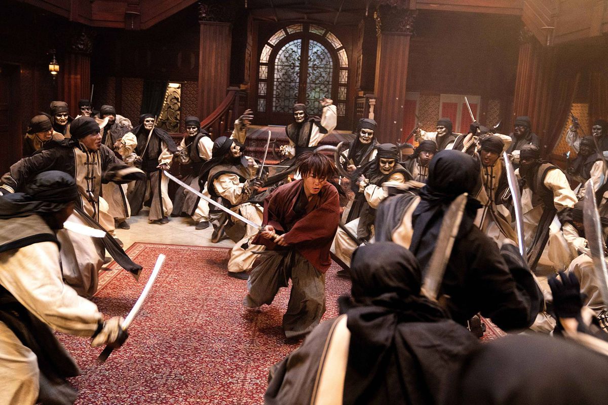 Kenshin carica attraverso una stanza di guerrieri mascherati e smascherati in Rurouni Kenshin: The Final