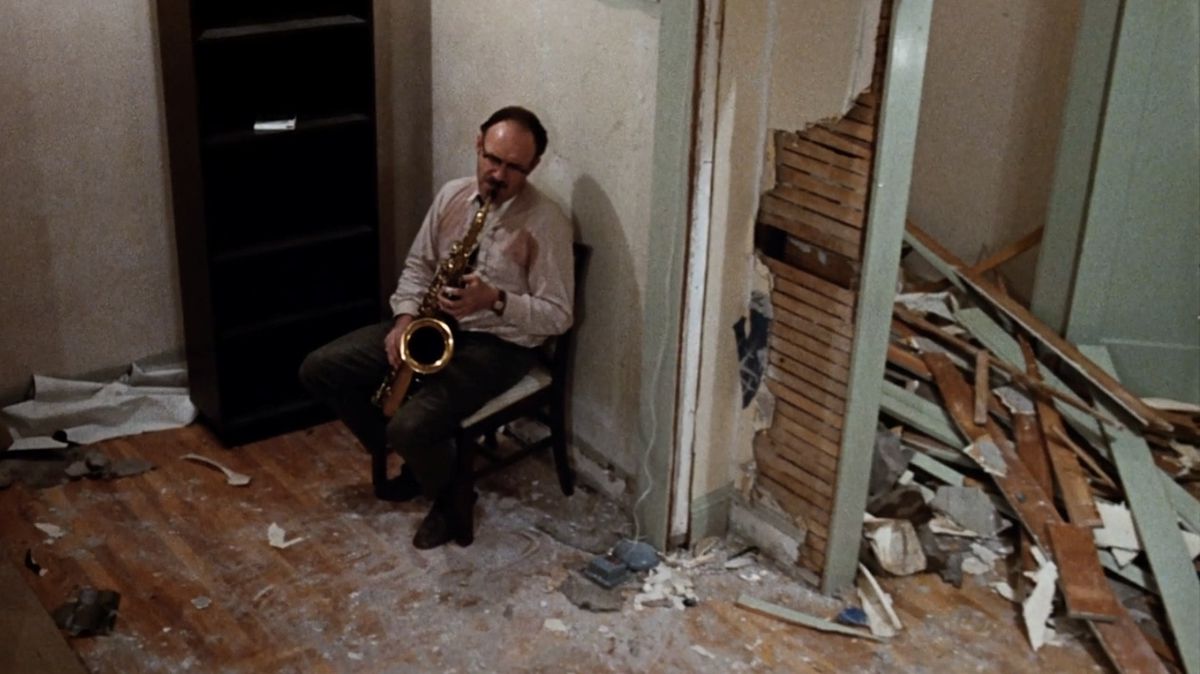 Gene Hackman nei panni di Harry Caul mentre suona il sassofono in un appartamento saccheggiato in The Conversation