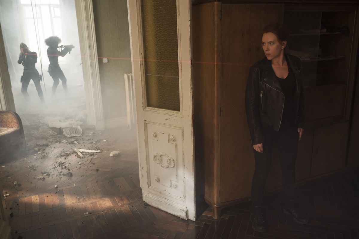 Natasha (Scarlett Johansson) si nasconde dietro il muro di un appartamento mentre le vedove nere con mitragliatrici entrano dalla porta