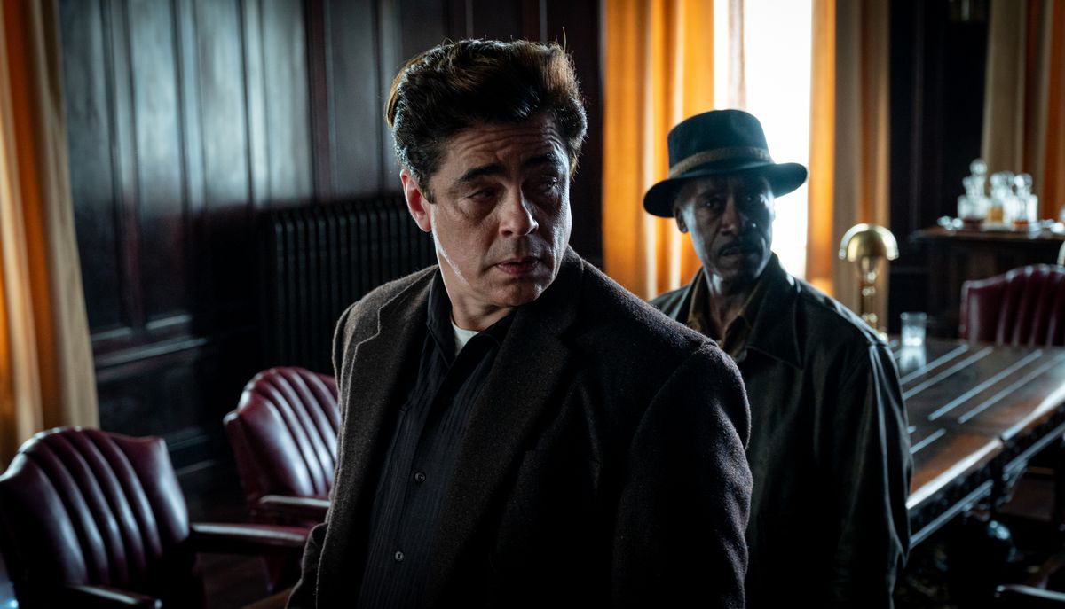 Benicio del Toro e Don Cheadle stanno in una stanza buia con tende luminose dietro di loro in No Sudden Move