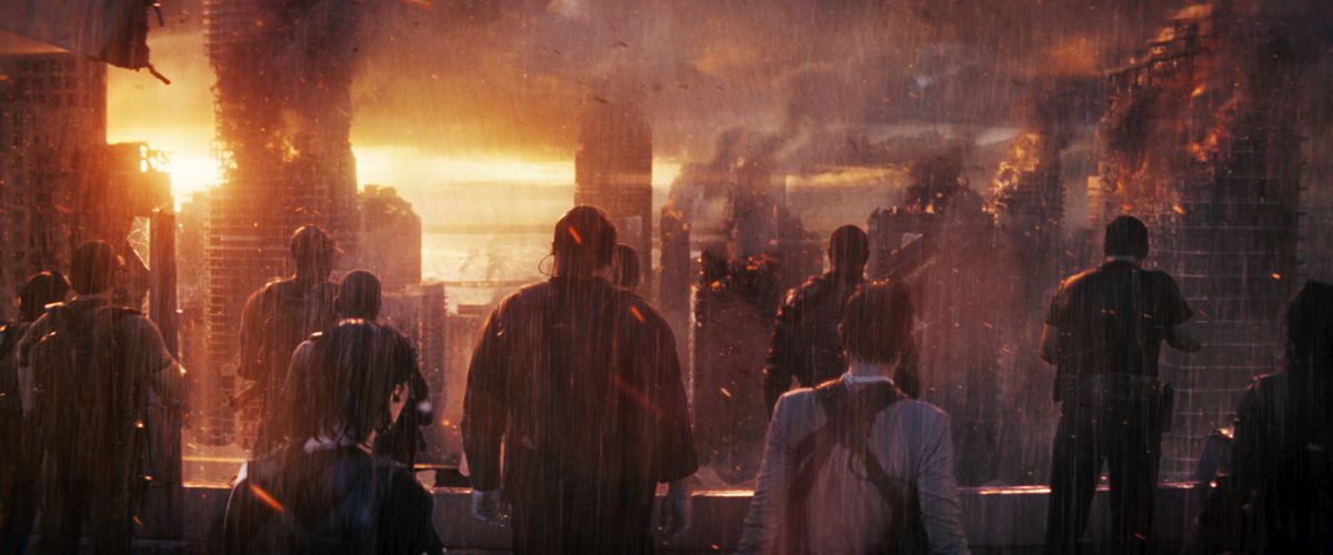 Una manciata di persone, viste da dietro, stanno sotto una pioggia torrenziale in CGI e guardano una città in CGI in fiamme in The Tomorrow War